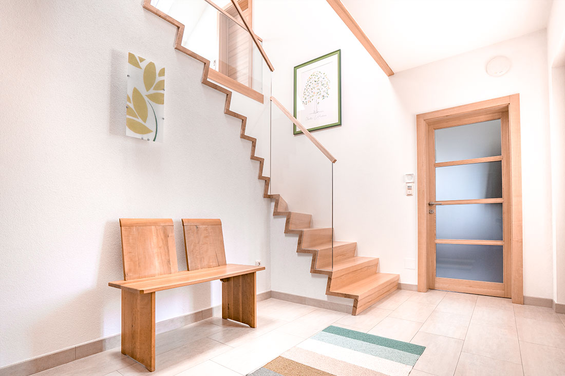 Großzügiges Treppenhaus mit eleganter Wendeltreppe aus Massivholz und Glasgeländer (Foto: Akkurat Identity)